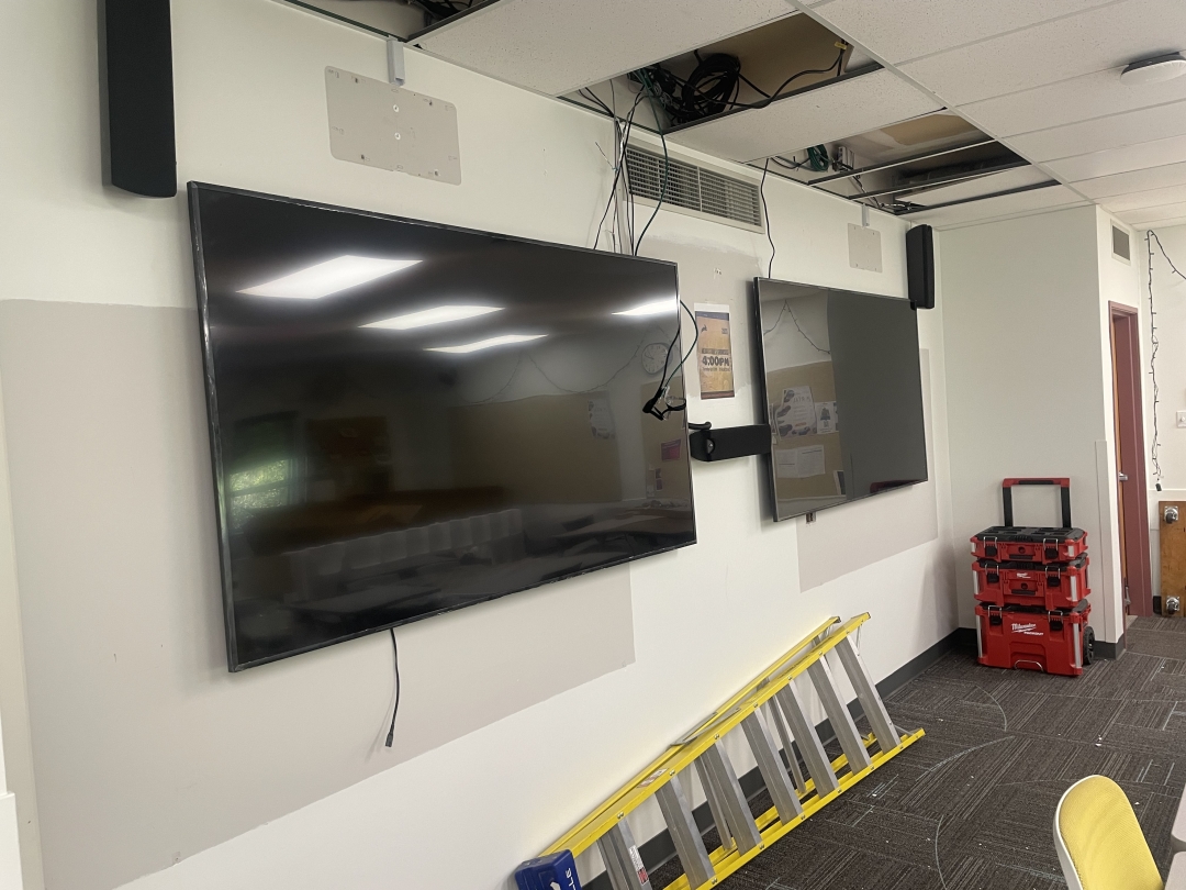Work in progress on new TVs A picture of the classroom shows two large TVs mounted on a long wall.