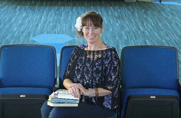Smiling woman with brown hair sitting on a theatre seat